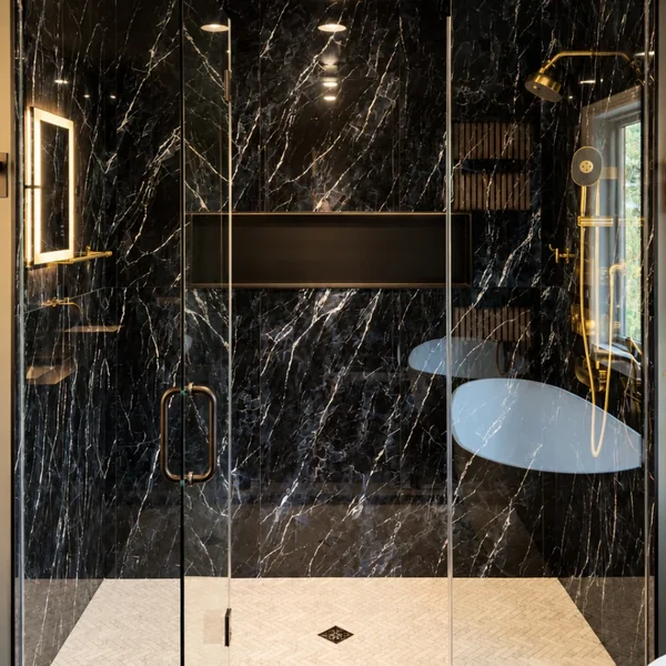 Black marble walk-in shower with gold fixtures and glass bench, Fairfield County CT